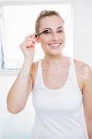 Young woman applying mascara in bathroom
