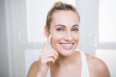 Young woman applying cream on face