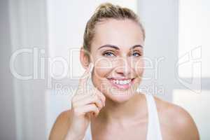 Young woman applying cream on face