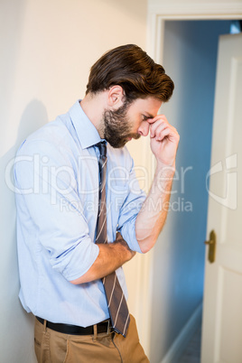Worried man with hand on forehead leaning on wall