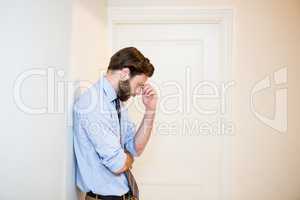 Worried man with hand on forehead leaning on wall