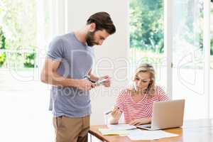 Man cutting a credit card while tense woman with bills sitting a
