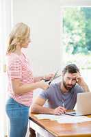 Woman cutting a credit card while tense man with bills sitting a