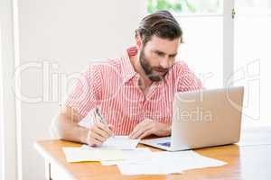 Young man using laptop while calculating a bills
