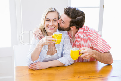 Man kissing woman while having coffee