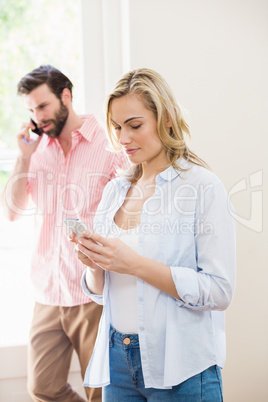 Woman texting messaging while man talking on mobile phone