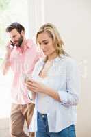 Woman texting messaging while man talking on mobile phone
