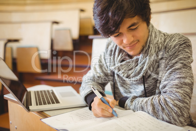 Young student sitting at a desk writing notes