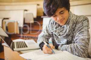 Young student sitting at a desk writing notes