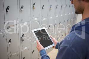 Student using digital tablet in locker room
