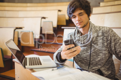 Young student sitting at desk using mobile phone
