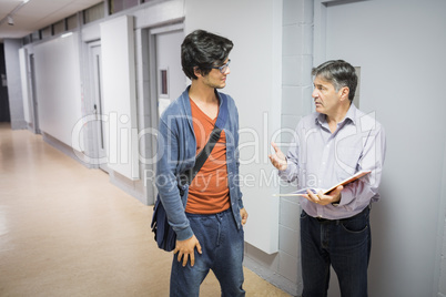 Professor with notebook talking to a student