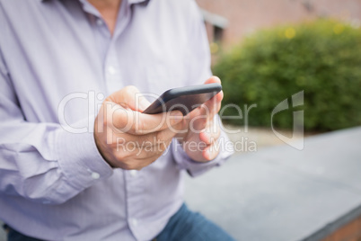 Mid section of a man using mobile phone