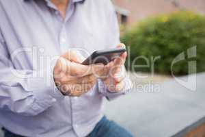 Mid section of a man using mobile phone