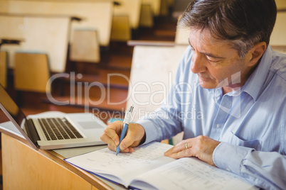 Professor writing in book at desk