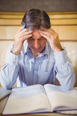 Depressed professor sitting with notes at desk