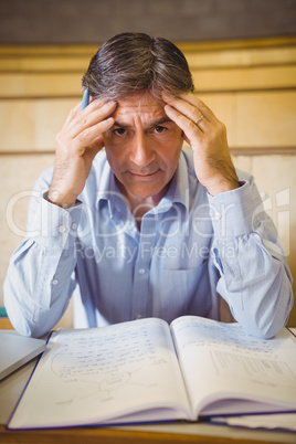 Portrait of depressed professor sitting with notes