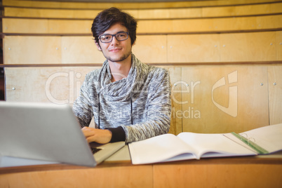 Portrait of smiling student using laptop in classroom