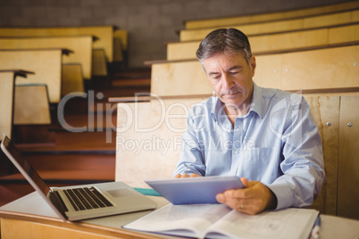 Professor sitting at desk using digital tablet