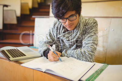 Young student sitting at a desk writing notes