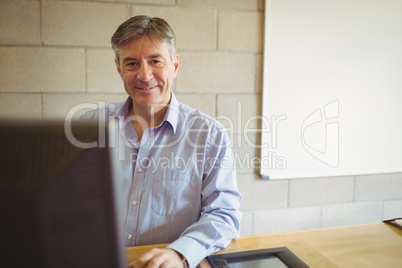 Portrait of professor sitting on desk