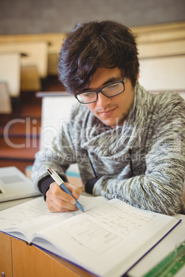 Young student sitting on desk reading notes