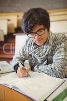 Young student sitting on desk reading notes