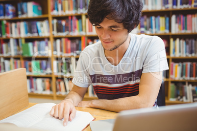 Young student sitting at desk reading a book