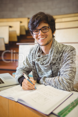 Portrait of young student sitting on desk reading notes