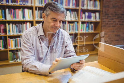 Professor sitting at desk using digital tablet