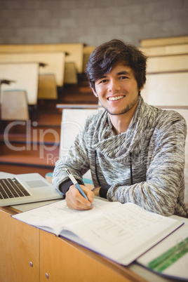 Portrait of young student sitting at desk reading notes
