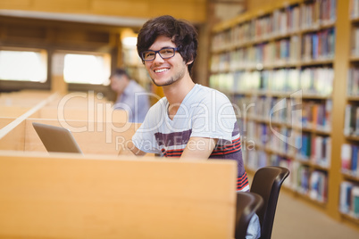 Portrait of happy young student using his laptop