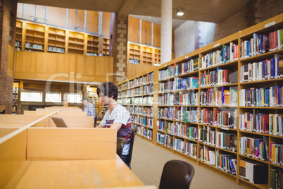 Young student using his laptop in library