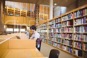 Young student using his laptop in library