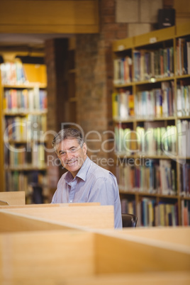 Portrait of happy professor sitting at desk