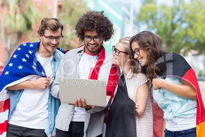 Friends holding national flag and using laptop