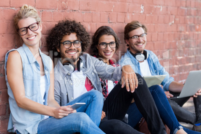 Portrait of friends sitting against wall