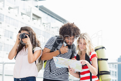 Woman clicking photo while her friends looking at map