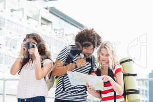 Woman clicking photo while her friends looking at map