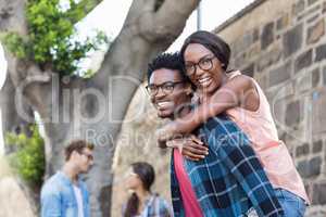 Young man giving piggyback to woman