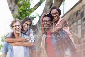 Young men giving piggyback to women