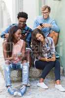 Friends sitting together using mobile phone