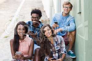 Friends sitting together using mobile phone