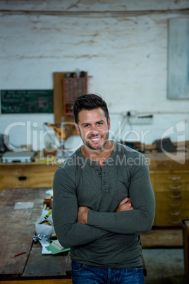 A carpenter is posing with his arms crossed