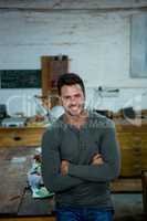 A carpenter is posing with his arms crossed