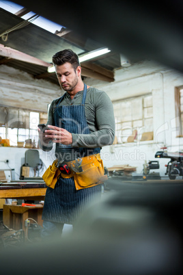 A carpenter is looking at his phone