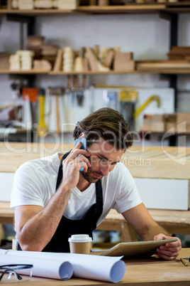 Carpenter calling someone and looking at his tablet