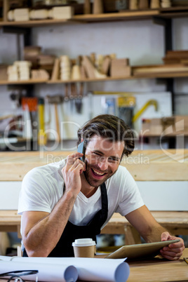 Carpenter calling someone and holding his tablet