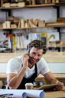 Carpenter calling someone and holding his tablet