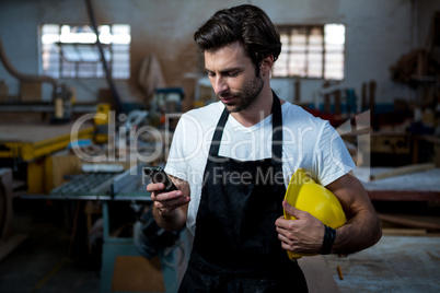 Carpenter texting someone and holding his helmet